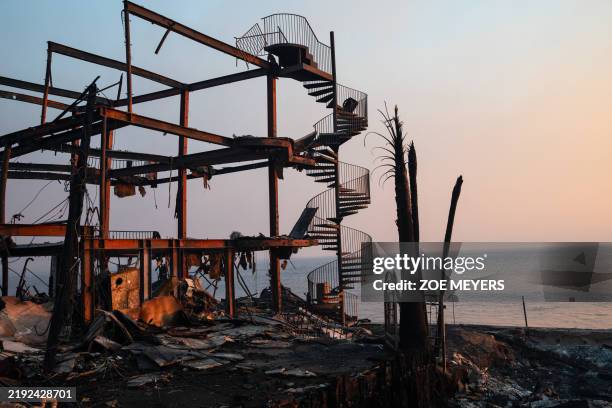 Spiral staircase stands amidst the smoldering skeleton of a house destroyed by the Palisades fire along the Pacific Coast Highway in Malibu,...
