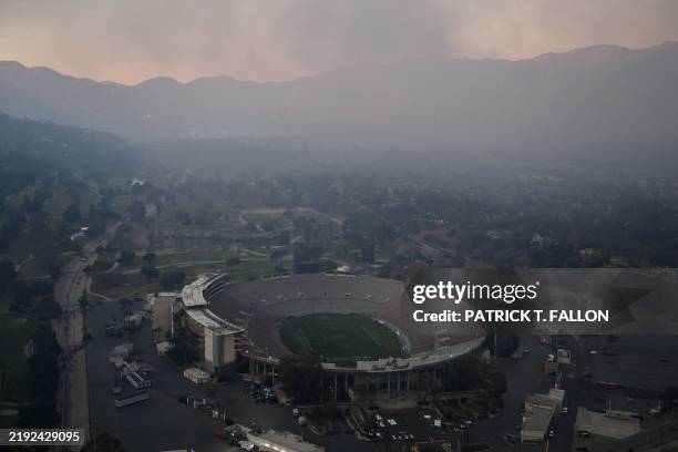 An aerial image shows smoke covering the hillsides behind the Rose Bowl stadium from wildfires including the Eaton Fire at sunset over Pasadena,...