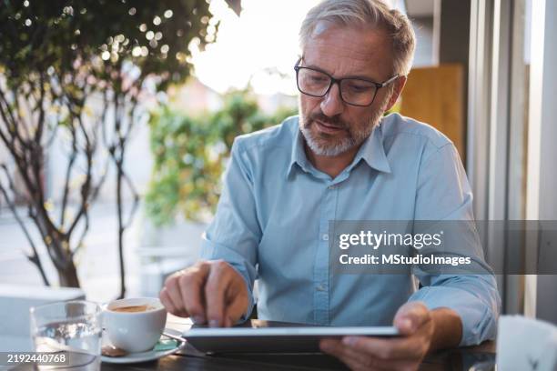 mature man using tablet to work from the bar - coffee testing stock pictures, royalty-free photos & images
