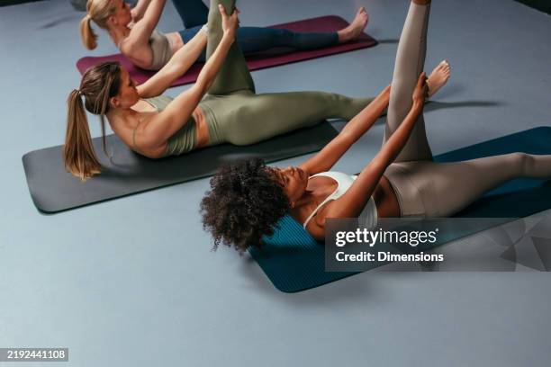 groupe de jeunes femmes faisant des exercices de pilates sur des tapis dans une salle de sport - tapis de sol photos et images de collection