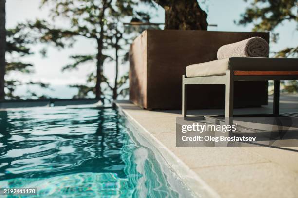 poolside with chaise lounge, towel and turquoise clear water in pool - bordo piscina foto e immagini stock