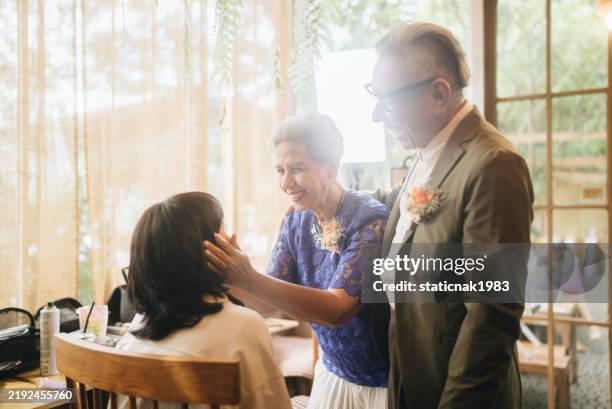 joyful bride bows respectfully to her elderly parents to receive their advice on married life before her wedding ceremony. - alte und junge lesbische frauen stock-fotos und bilder