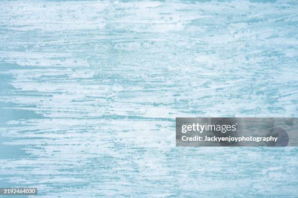 full-frame image of a river's frozen surface with fractures and shattered turquoise-blue ice crystals. - nappage photos et images de collection