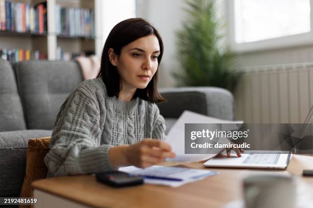 woman planning her finances, reviews paperwork for insurance, loans, and online investments - online bank statement stock pictures, royalty-free photos & images