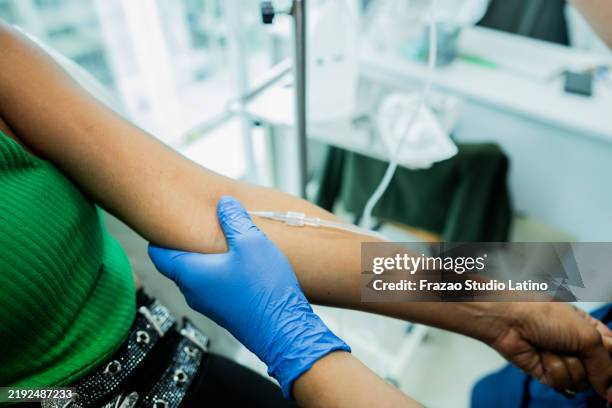 close-up of a doctor putting iv drip on patient on a doctor's office - infuus met een fysiologische zoutoplossing stockfoto's en -beelden