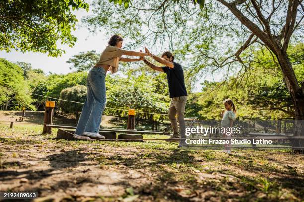 eltern beim slackline-spielen im freizeitpark - slackline stock-fotos und bilder