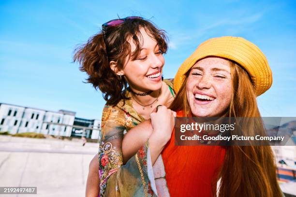 young woman wearing yellow sunhat giving female friend piggyback - vestido amarelo imagens e fotografias de stock