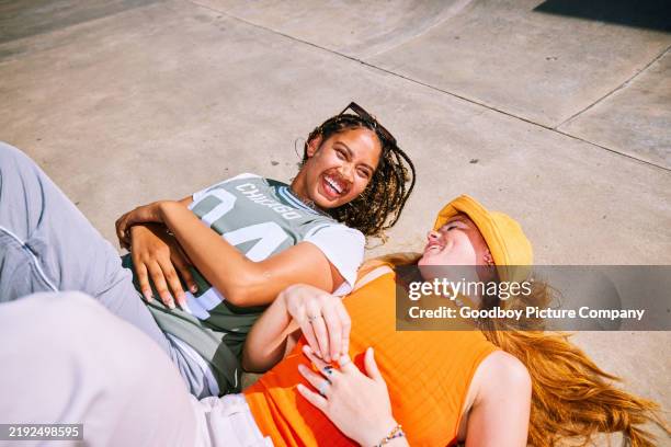 zwei freundinnen, die auf dem rücken liegen, seite an seite, lächelnd und redend - nur junge frauen stock-fotos und bilder