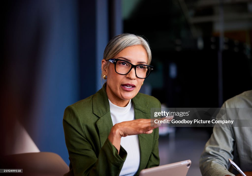Serious mature businesswoman with gray hair and glasses, gesturing and explaining
