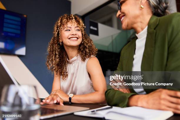 cheerful young businesswoman smiling confidently towards female colleague at work - coach stockfoto's en -beelden