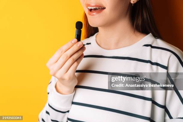 young woman holding a wireless small microphone in her hand and speaking - revers stock-fotos und bilder