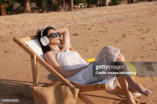 a serene beach scene with a woman in a white dress, lying on a bed under the sun. females relax and enjoy a beach outdoor activity lifestyle on summer holiday vacation - sunbathing stock pictures, royalty-free photos & images