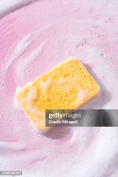 yellow sponge with soap suds scrubbing on pink background - bath sponge stock pictures, royalty-free photos & images