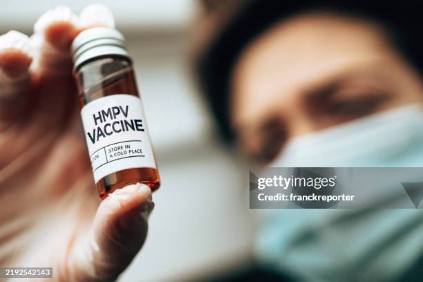 holding the hmpv vaccine vials - humaan metapneumovirus stockfoto's en -beelden