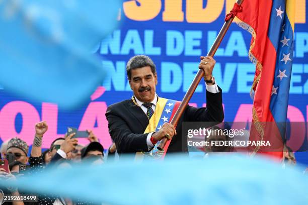 Venezuela's President Nicolas Maduro waves a Venezuelan flag after delivering a speech in front of Miraflores presidential palace in Caracas on...