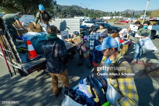 Pasadena, CA Volunteers help people load bags of goods at a large donation site has sprung up outside the Rose Bowl. It started out as a way to feed...