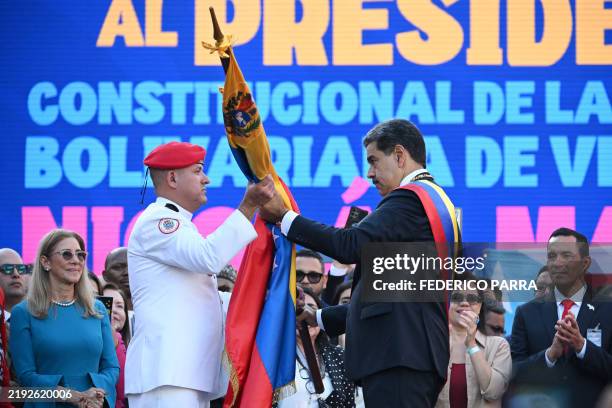 Venezuela's President Nicolas Maduro receives a Venezuelan flag from a Military Commander in front of Miraflores presidential palace in Caracas on...