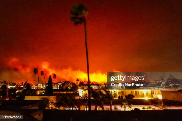 Flames illuminate the night sky as a wildfire burns across a hillside in Pacific Palisades, California, on January 7, 2025. The most destructive...