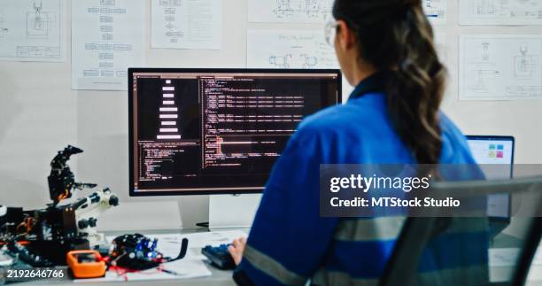 young female engineer works on controlling a robotic arm in tech lab. display ai and robotics hand design operates machinery and analyzes data for innovation. ai and robotics development. - invento fotografías e imágenes de stock