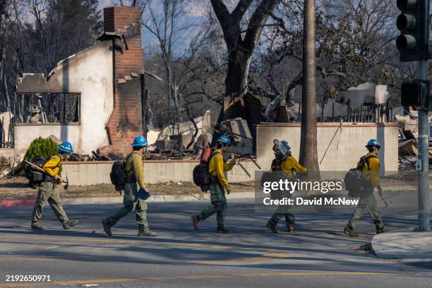 Wildland firefighters in a hotshot crew from near Klamath, Oregon search the ruins of houses in a neighborhood where many homes were destroyed by the...