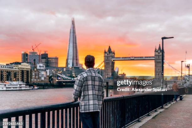 man looking at london skyline featuring tower bridge and the shard skyscraper at sunset, england, uk - central london stock pictures, royalty-free photos & images