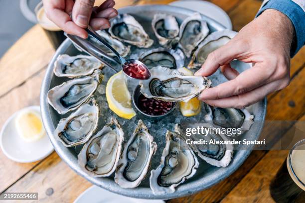 man eating oysters with vinegar sauce at a restaurant, close-up - oyster stock pictures, royalty-free photos & images