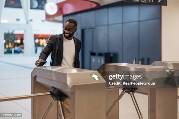 businessman using smartphone to pass through turnstile gate in airport - entrance gate stock pictures, royalty-free photos & images