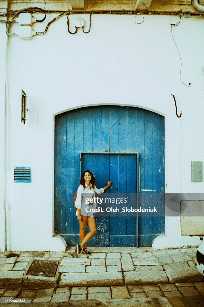 Woman standing near the blue door exploring the island in Greece. Shot on camera film