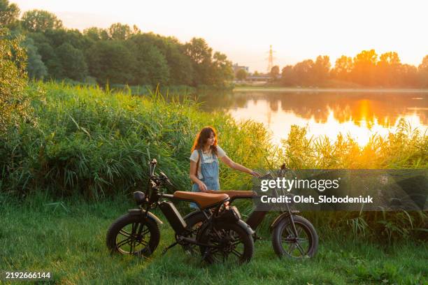 woman with electric bicycle at the lake in summer - alternative fuel vehicle stock pictures, royalty-free photos & images