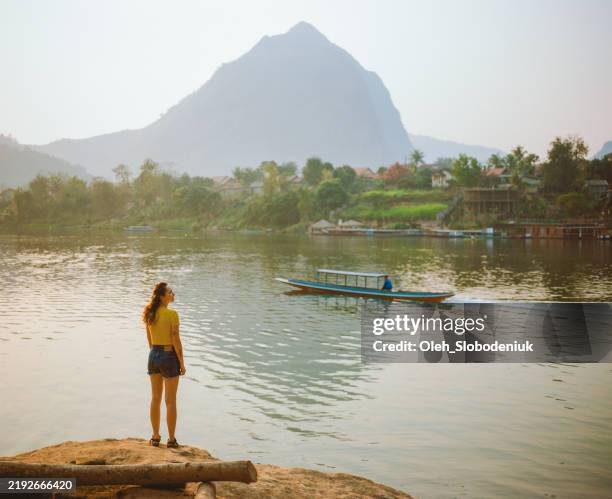 woman watching sunset from mekong riverbank in luang prabang. shot on film camera - laos stock pictures, royalty-free photos & images