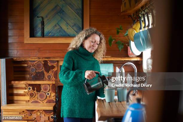 a senior woman making coffee in an eco lodge - realism stock pictures, royalty-free photos & images
