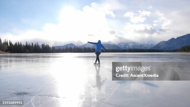 woman skates on frozen pond - kananaskis country stock pictures, royalty-free photos & images