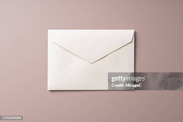 white envelope on brown background - correspondencia fotografías e imágenes de stock