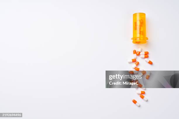 many capsules spilled from a pill bottle - tablettenbehälter stock-fotos und bilder