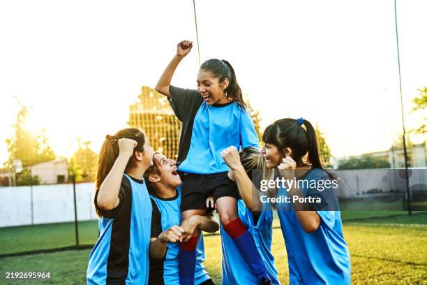 girls soccer player carrying teammate on shoulders after win - atlete stockfoto's en -beelden