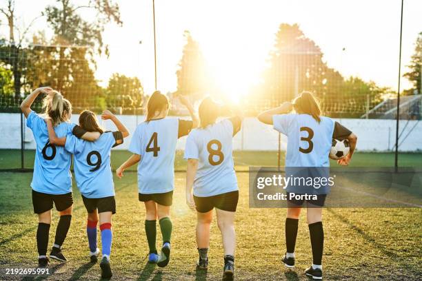 rear view of teenage girls soccer team with their trophy on the field - soccer competition stock pictures, royalty-free photos & images