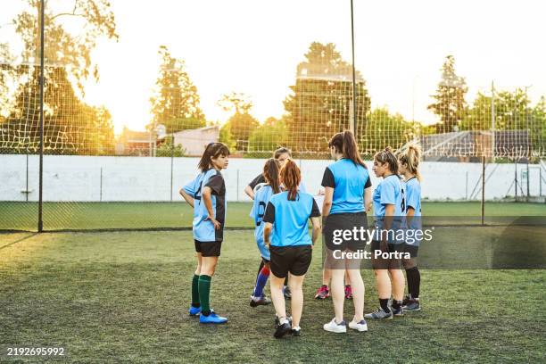 girls soccer team discussing game plan on sunny sports court - club football stock pictures, royalty-free photos & images
