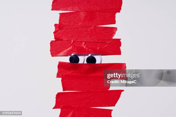 googly eyes covered by red tape, bureaucracy concept - wackelaugen stock-fotos und bilder