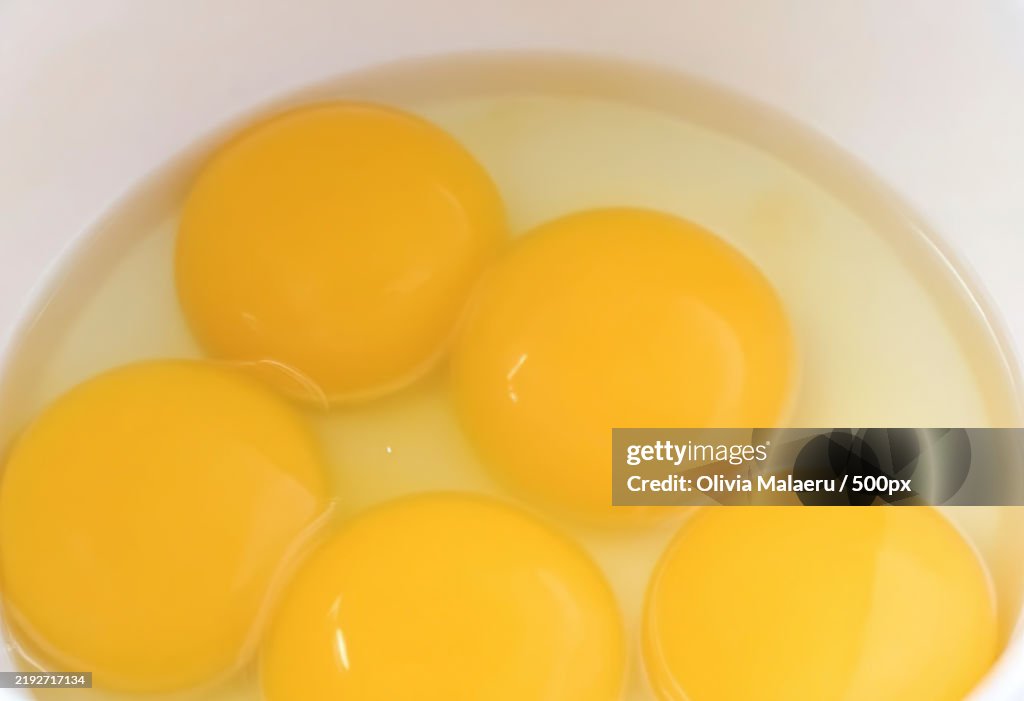 A bowl containing several raw eggs with a glossy yolk