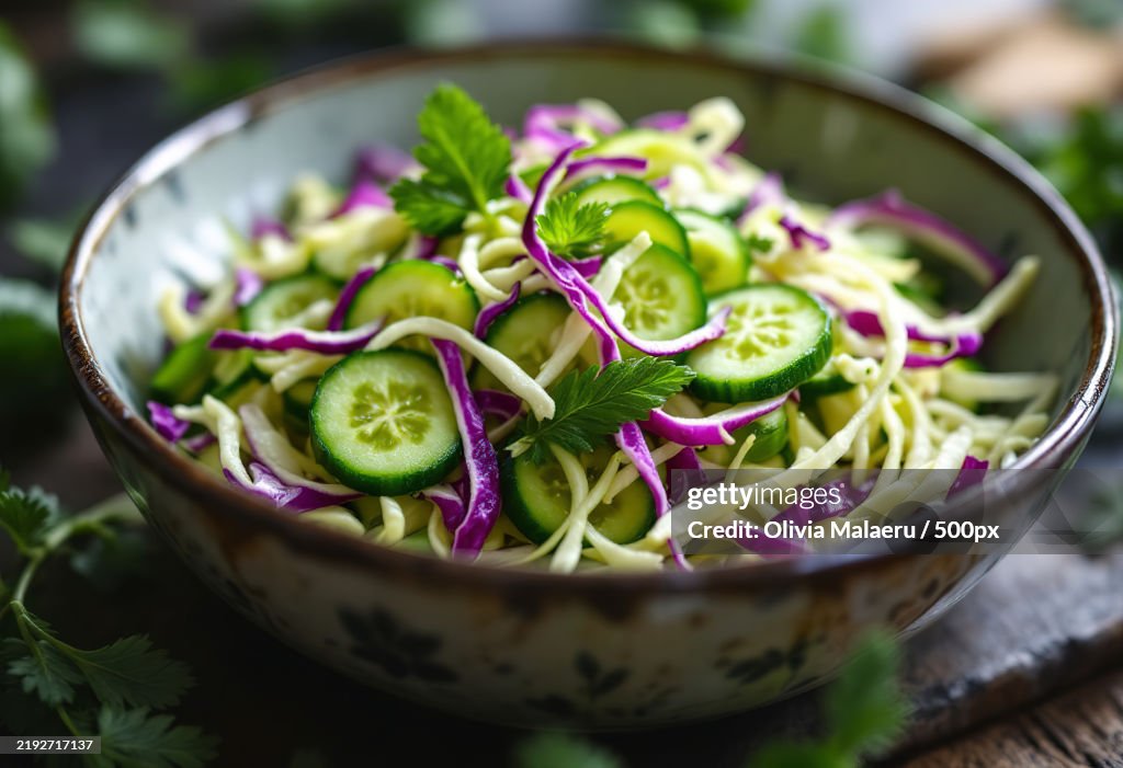 A close-up shot of a fresh organic cucumber salad with shredded cabbage