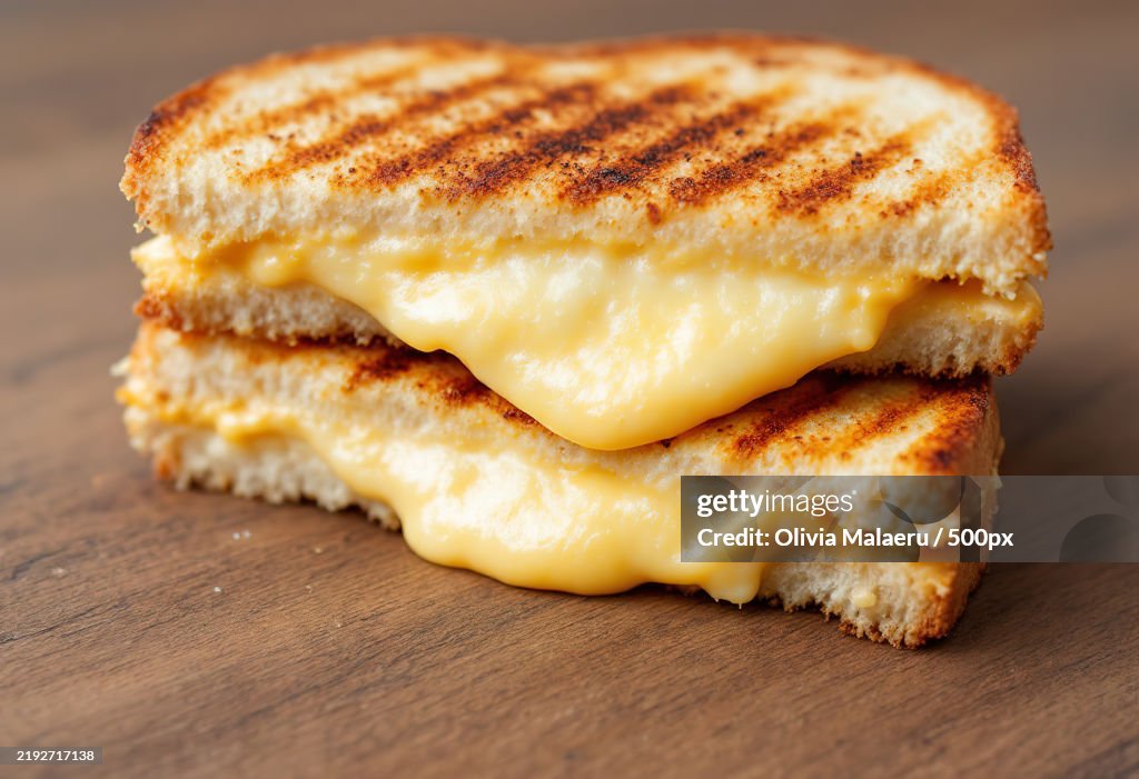 A close-up view of a grilled sandwich,Cut in half,Revealing its gooey,Melted cheese filling