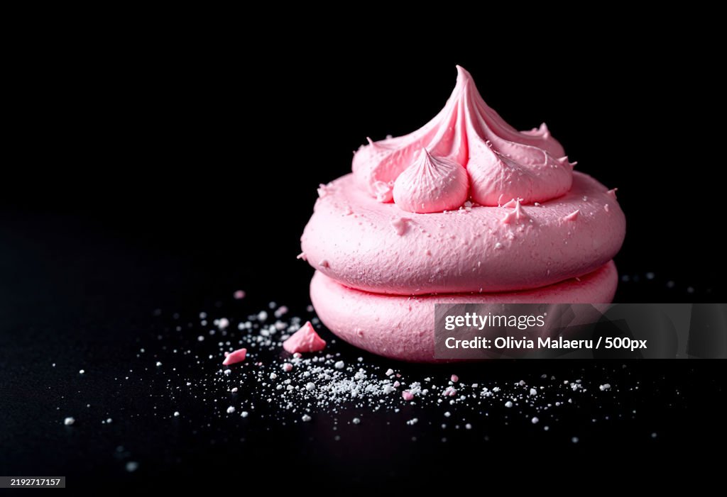 A pink meringue cookie isolated on a black background