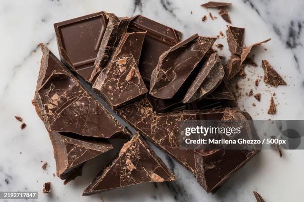 a marble surface with chunks and shavings of dark chocolate - cioccolato scuro foto e immagini stock