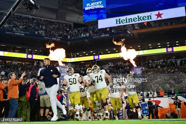 Head coach Marcus Freeman of the Notre Dame Fighting Irish leads the team to the field prior to the 2025 Orange Bowl against the Penn State Nittany...