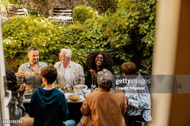 happy male and female family members having fun at dinner party in back yard - family dinner party stock pictures, royalty-free photos & images