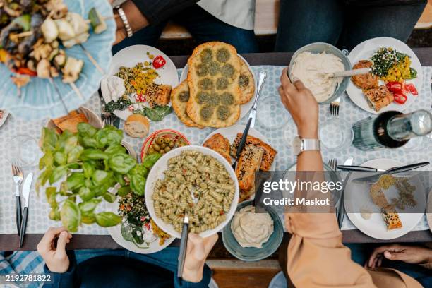 directly above shot of family members giving food bowls to each other while having dinner in back yard - cena con amigos fotografías e imágenes de stock