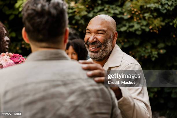 happy senior man with hand on shoulder of male friend at dinner party - hand on shoulder stock pictures, royalty-free photos & images