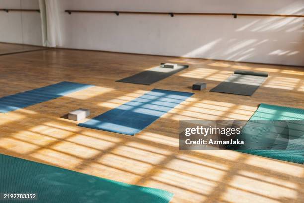 unfolded yoga mats in a pilates studio illuminated by sunlight - yoga studio stock pictures, royalty-free photos & images
