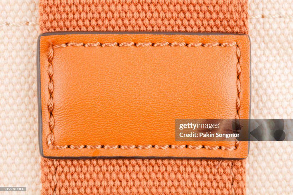 Brown leather blank label or tag on canvas textile background.