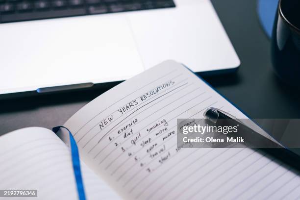 notebook with new year's resolutions listed and pen resting on page - new years day stock pictures, royalty-free photos & images